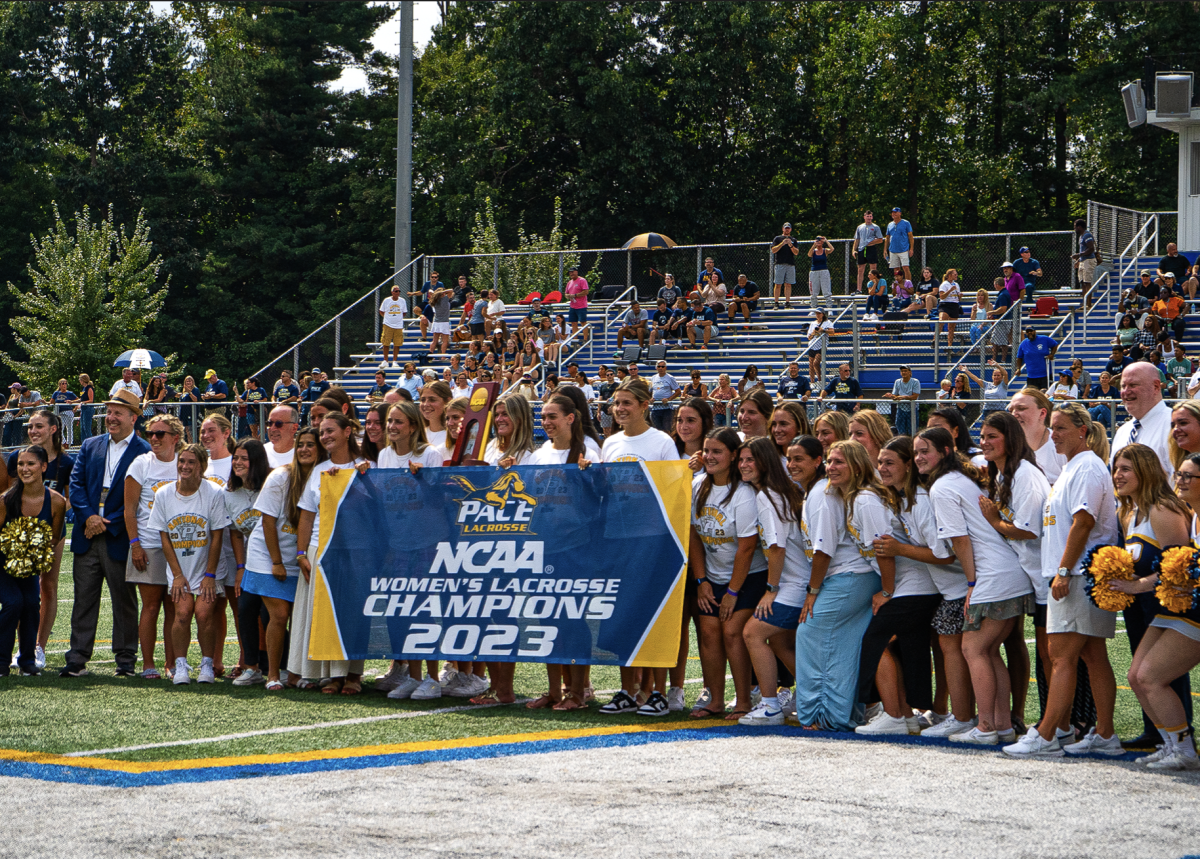 The 2023 Division II Womens Lacrosse Champions are honored at halftime, posing with a banner of their accomplishment in front of the home crowd